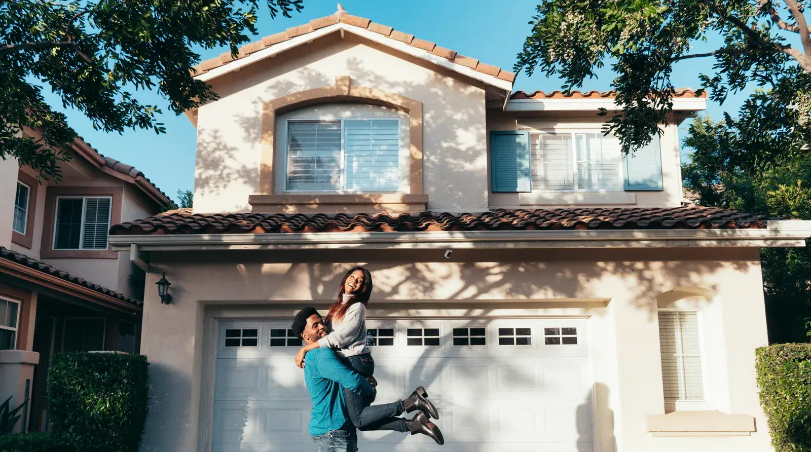 A couple celebrating in front of a new home